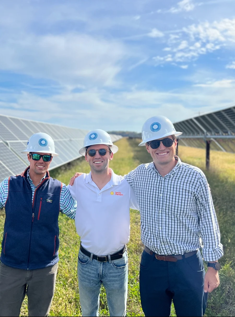 Gateway team members wearing hard hats between rows of solar panels